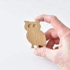 Hand holding handmade oak owl drawer knob showing natural wood grain and woodland animal shape