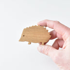 Hand holding handmade oak hedgehog drawer knob showing natural wood grain and woodland animal shape
