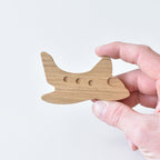Hand holding handmade oak aeroplane drawer knob showing porthole detail and natural wood grain