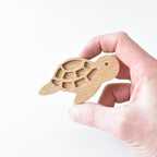 Hand holding handmade oak turtle drawer knob showing shell detail and natural wood grain