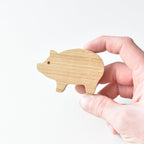 Hand holding handmade oak pig drawer knob showing natural wood grain and shape