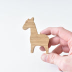 Hand holding handmade oak giraffe drawer knob showing natural wood grain and safari animal shape