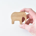 Hand holding handmade oak elephant drawer knob showing natural wood grain