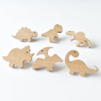 Set of six handmade oak dinosaur drawer knobs showing natural wood grain and raised detail