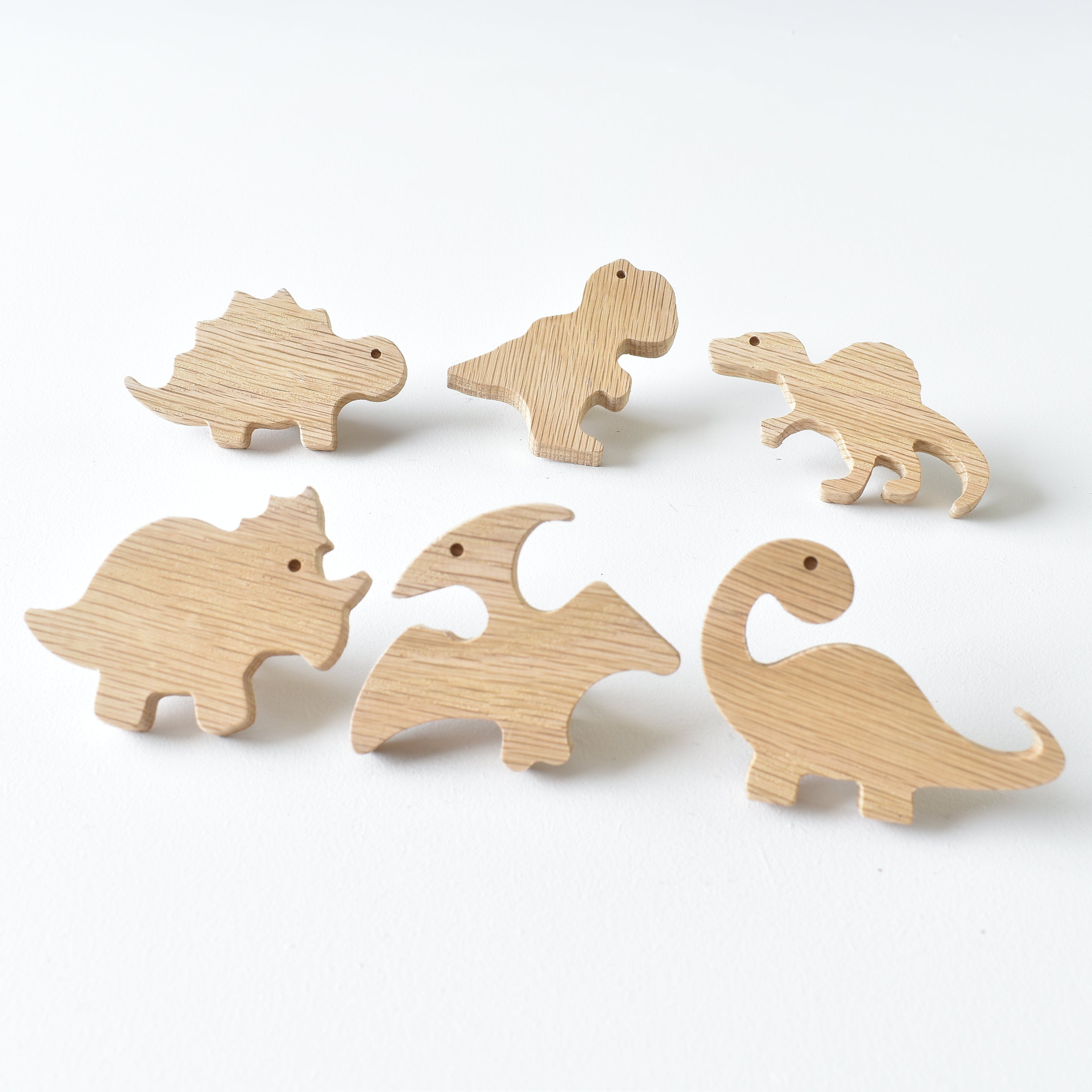 Set of six handmade oak dinosaur drawer knobs showing natural wood grain and raised detail