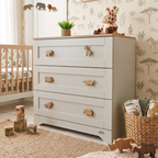 Oak safari animal drawer knobs fitted to a white nursery chest of drawers in a children’s bedroom